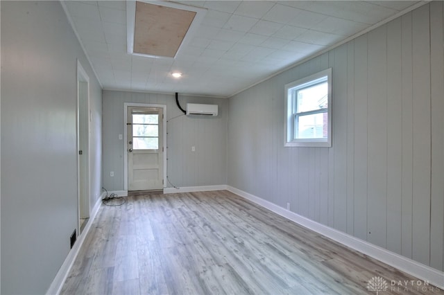 interior space featuring an AC wall unit, ornamental molding, wooden walls, and light hardwood / wood-style flooring