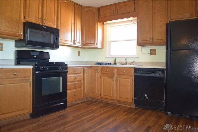 kitchen featuring black appliances, dark hardwood / wood-style flooring, and sink