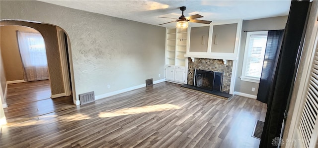 unfurnished living room featuring hardwood / wood-style flooring, a healthy amount of sunlight, a tile fireplace, and ceiling fan