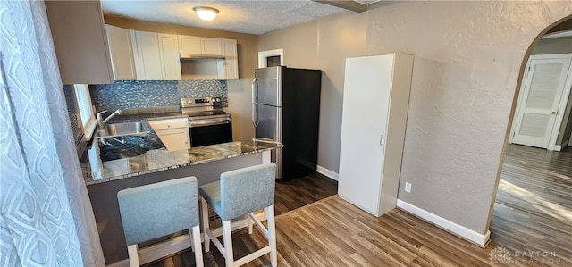 kitchen featuring kitchen peninsula, white cabinets, hardwood / wood-style floors, sink, and stainless steel appliances