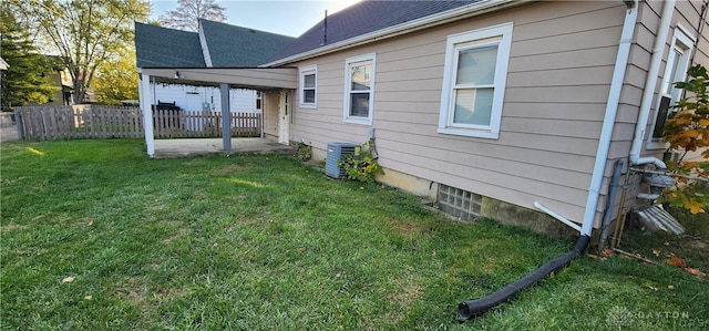 view of side of property featuring a patio, a lawn, and central AC unit