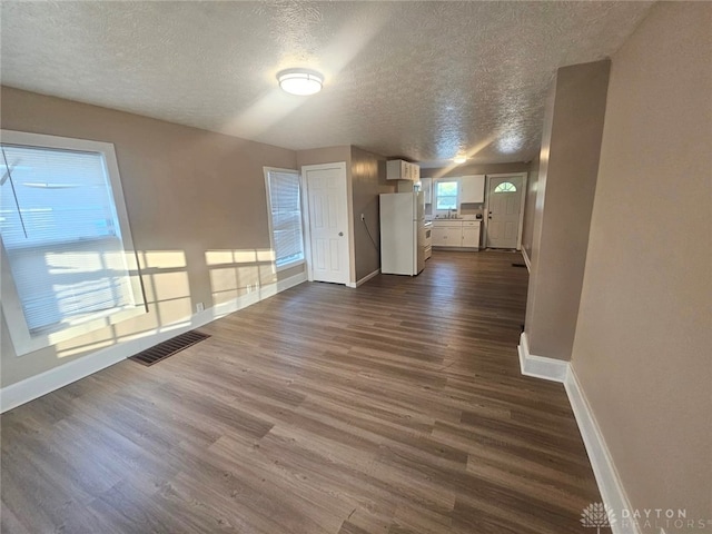 unfurnished living room featuring a textured ceiling and dark wood-type flooring