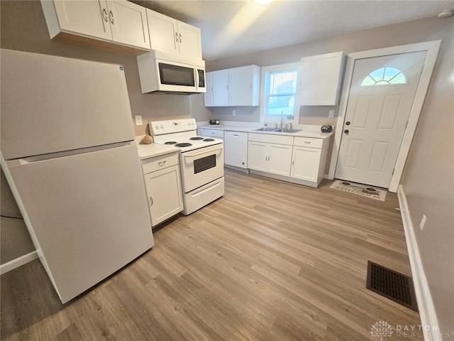 kitchen with white cabinets, sink, light wood-type flooring, and white appliances