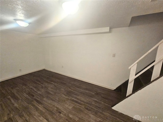 spare room with a textured ceiling and dark hardwood / wood-style floors