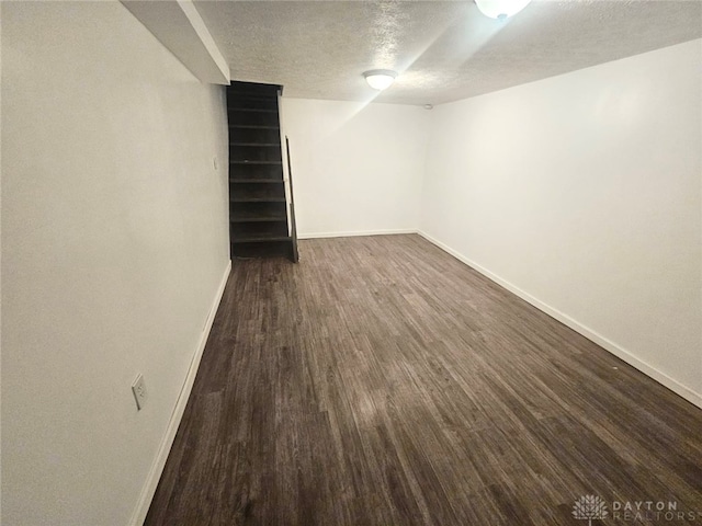 basement featuring a textured ceiling and dark wood-type flooring