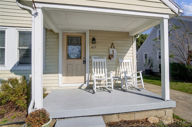 view of exterior entry featuring central AC unit and a porch