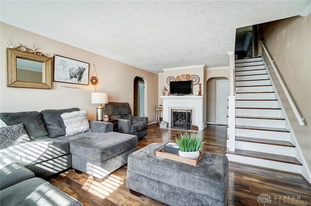 living room with a textured ceiling, ornamental molding, and dark wood-type flooring