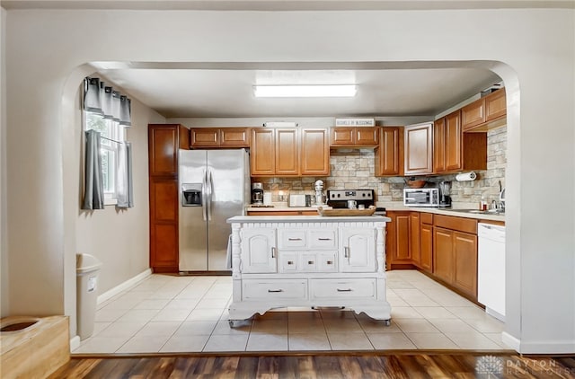 kitchen with appliances with stainless steel finishes, backsplash, and light hardwood / wood-style flooring