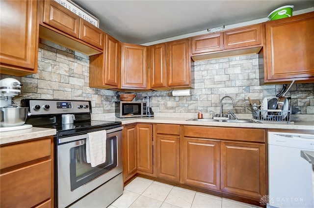 kitchen featuring tasteful backsplash, sink, light tile patterned floors, and stainless steel appliances