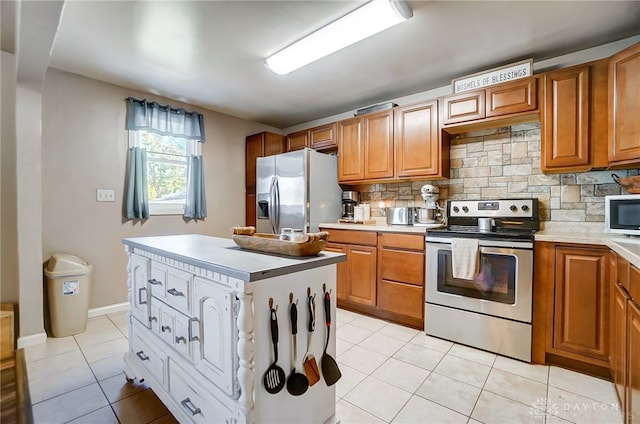 kitchen featuring decorative backsplash, a center island, light tile patterned floors, and appliances with stainless steel finishes