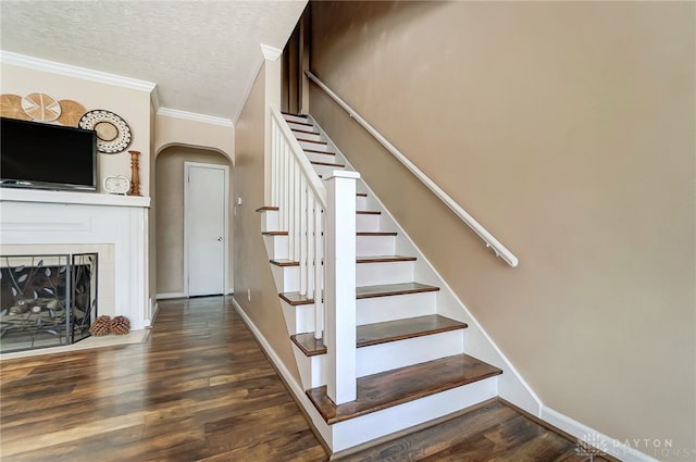 stairs featuring hardwood / wood-style floors, a textured ceiling, and ornamental molding