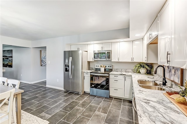 kitchen featuring appliances with stainless steel finishes, white cabinets, sink, and light stone counters