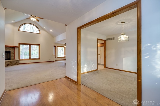 unfurnished living room featuring a fireplace, a wealth of natural light, ceiling fan, and vaulted ceiling