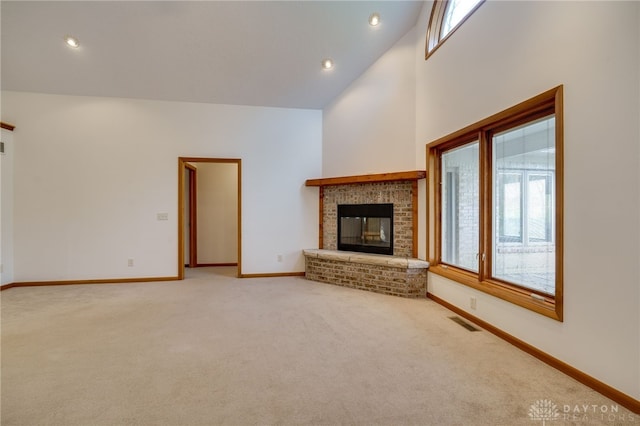 unfurnished living room with carpet floors, a brick fireplace, and a high ceiling