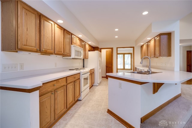 kitchen with a kitchen bar, sink, white appliances, and kitchen peninsula