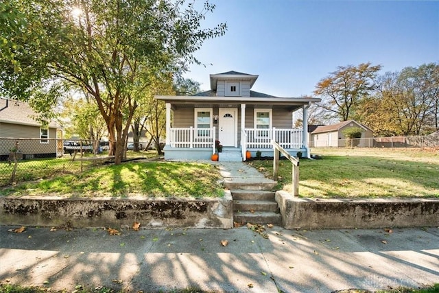 bungalow-style home with covered porch, a front lawn, and fence