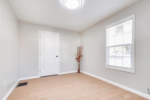 spare room with baseboards, visible vents, and wood finished floors