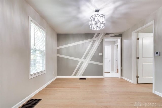 unfurnished dining area with light wood-style flooring, visible vents, and baseboards