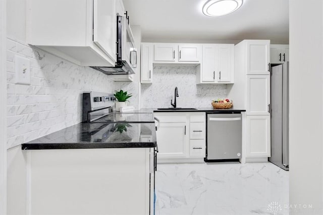 kitchen featuring stainless steel appliances, a sink, white cabinetry, marble finish floor, and backsplash