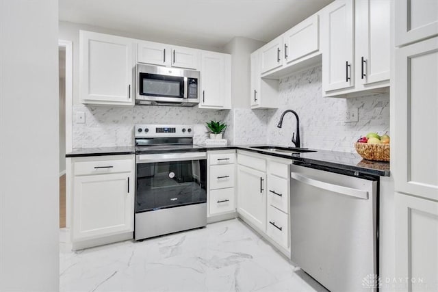 kitchen with marble finish floor, stainless steel appliances, dark countertops, and a sink