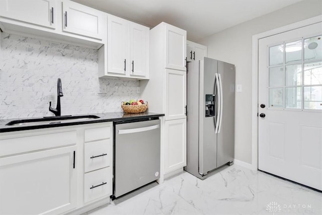 kitchen featuring marble finish floor, tasteful backsplash, appliances with stainless steel finishes, white cabinets, and a sink