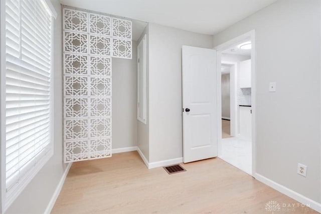 unfurnished bedroom featuring wood finished floors, visible vents, and baseboards