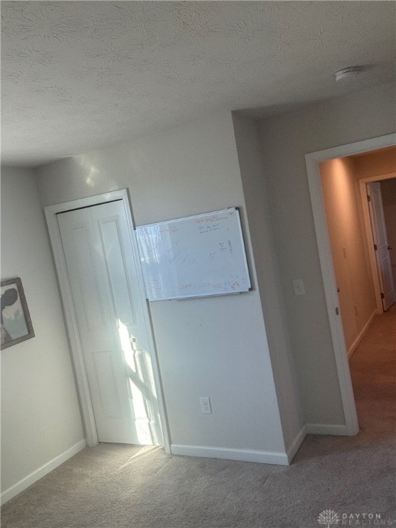 unfurnished bedroom with a closet, carpet, and a textured ceiling