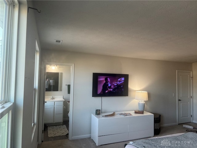 carpeted bedroom featuring sink, a textured ceiling, and ensuite bathroom