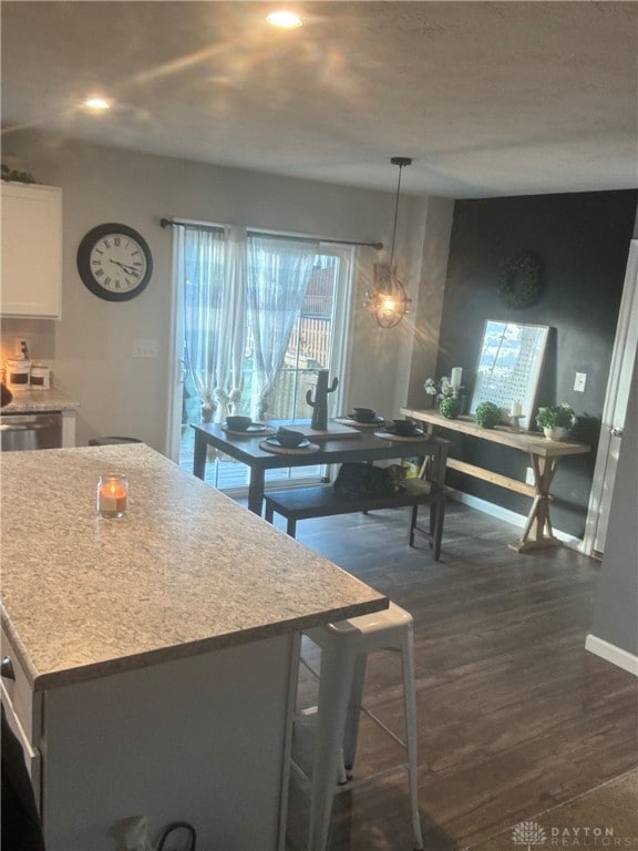 kitchen with a kitchen island, white cabinetry, decorative light fixtures, a kitchen bar, and dark hardwood / wood-style floors