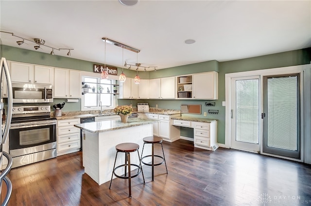 kitchen with a kitchen island, dark wood-type flooring, stainless steel appliances, pendant lighting, and white cabinets