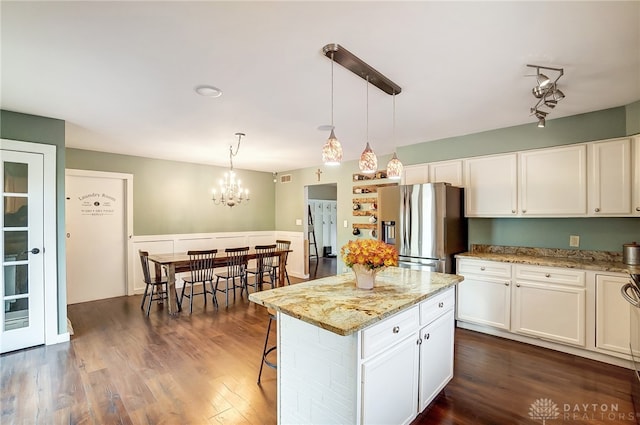 kitchen featuring a kitchen island, stainless steel fridge with ice dispenser, pendant lighting, and white cabinetry