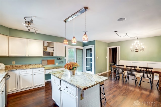 kitchen with dark hardwood / wood-style floors, pendant lighting, a kitchen island, and white cabinets