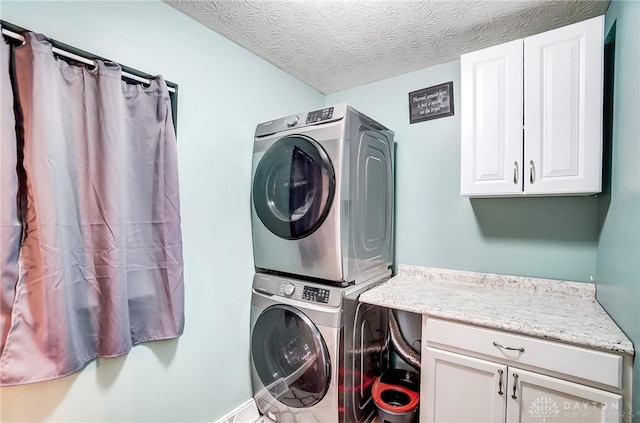 clothes washing area featuring a textured ceiling, cabinets, and stacked washer and clothes dryer