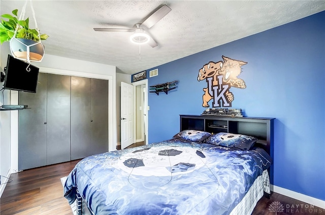 bedroom featuring dark wood-type flooring, ceiling fan, a closet, and a textured ceiling