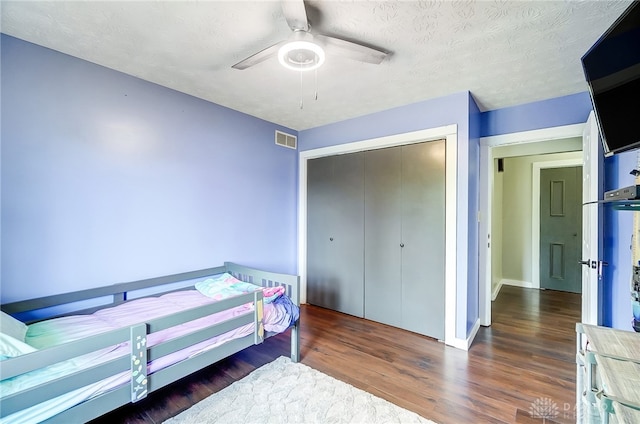 bedroom featuring a closet, ceiling fan, a textured ceiling, and dark hardwood / wood-style floors