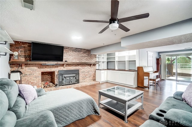 living room with hardwood / wood-style flooring, a wood stove, brick wall, a textured ceiling, and ceiling fan