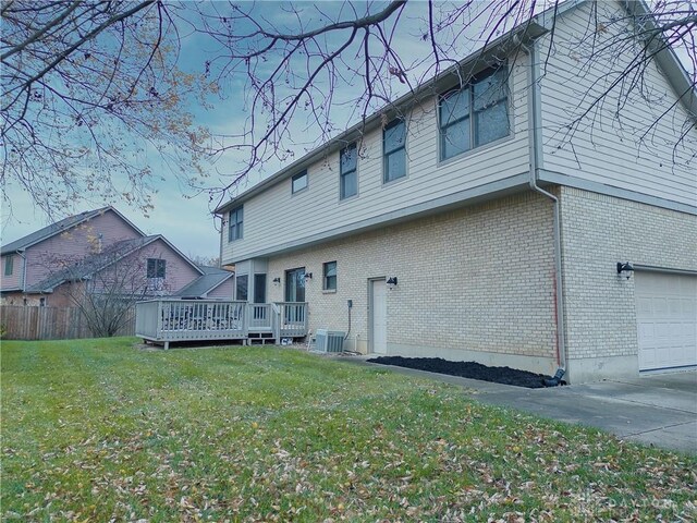 back of property featuring central AC unit, a yard, a garage, and a wooden deck