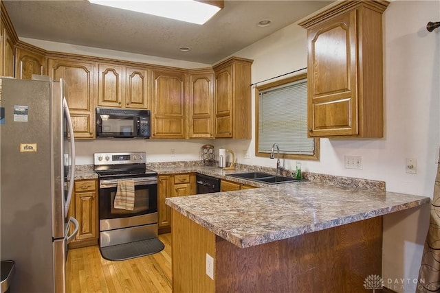 kitchen featuring light hardwood / wood-style flooring, kitchen peninsula, black appliances, and sink