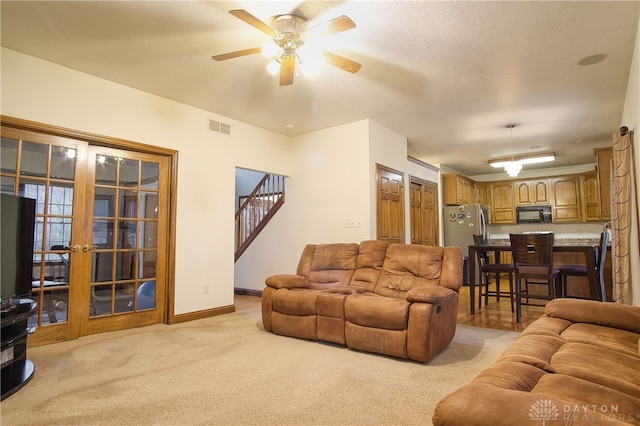 living room with a textured ceiling, ceiling fan, and light carpet