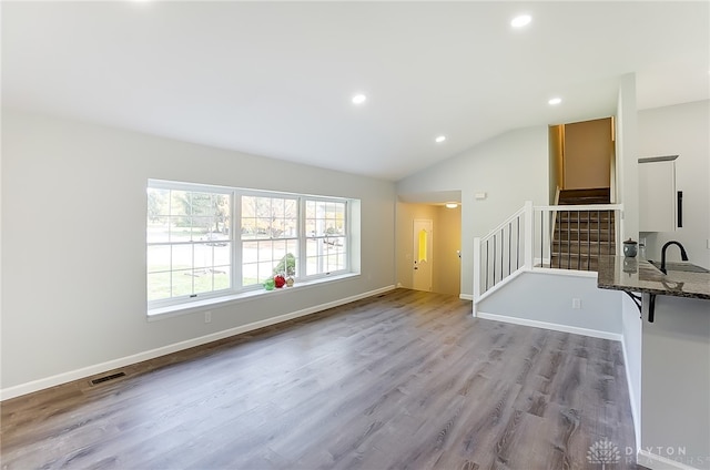 spare room featuring lofted ceiling, sink, and light hardwood / wood-style flooring