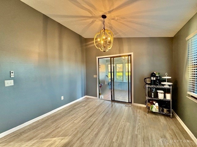 empty room with an inviting chandelier, hardwood / wood-style floors, and a wealth of natural light