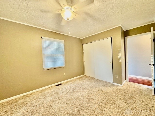 unfurnished bedroom featuring a textured ceiling, carpet flooring, a closet, and ceiling fan