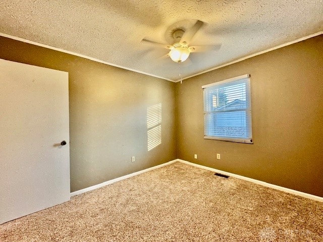 carpeted spare room featuring ceiling fan, crown molding, and a textured ceiling