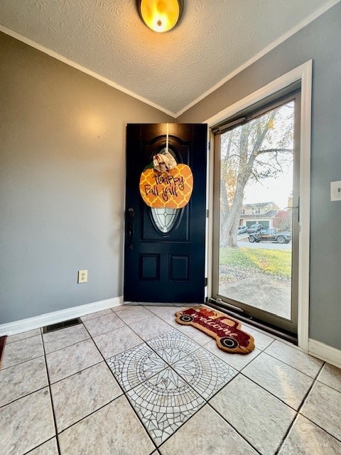 tiled entryway featuring crown molding, vaulted ceiling, and a textured ceiling