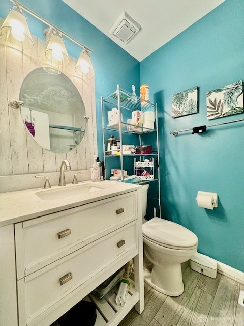 bathroom with toilet, hardwood / wood-style flooring, and vanity