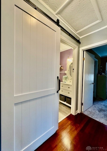 corridor with wood-type flooring, a textured ceiling, and a barn door