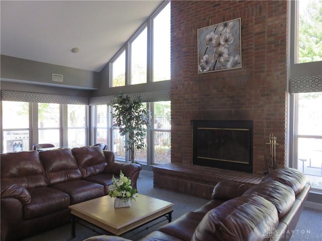 living area featuring high vaulted ceiling, plenty of natural light, a fireplace, and visible vents