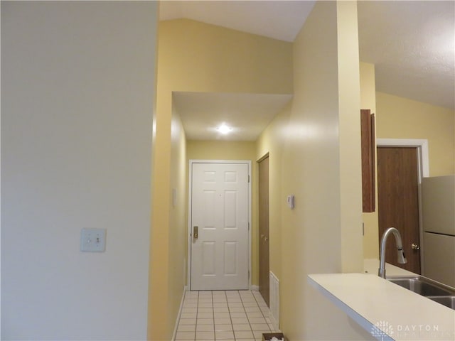 interior space featuring sink, light tile patterned floors, and vaulted ceiling