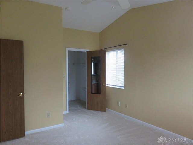 unfurnished bedroom featuring lofted ceiling, light carpet, ceiling fan, a spacious closet, and a closet