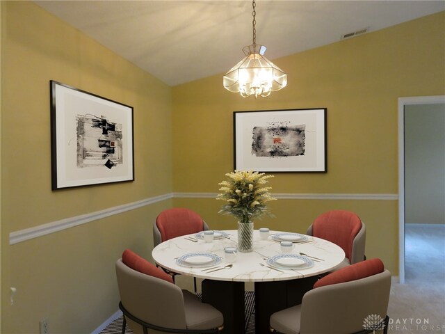 carpeted dining room with a chandelier